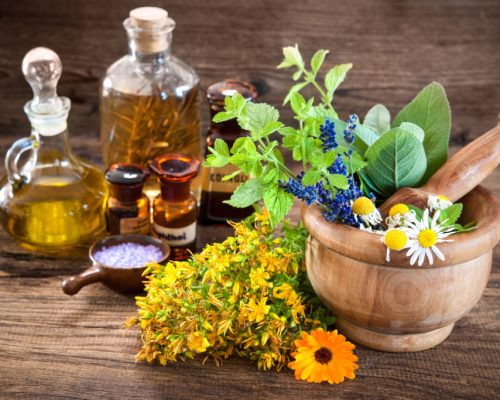 Essential oil, mortar with fresh herbs and bath salt on wooden background